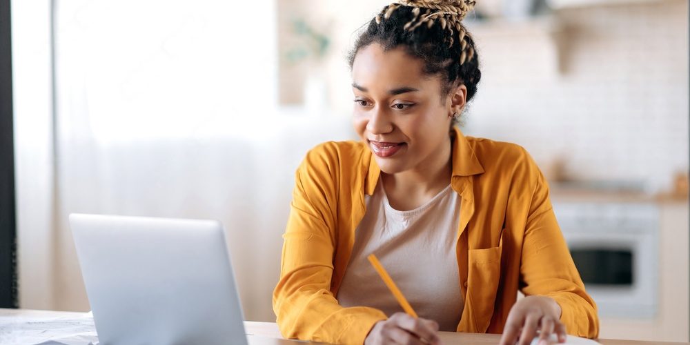 Woman taking notes while learning from and elearning website platform