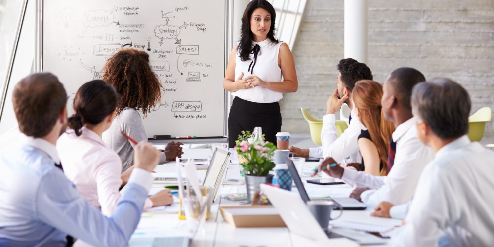 Hispanic Businesswoman Leading Solution Implementation Meeting At Boardroom Table